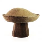 Side view of large round and shallow beret with the edges sightly tilted.